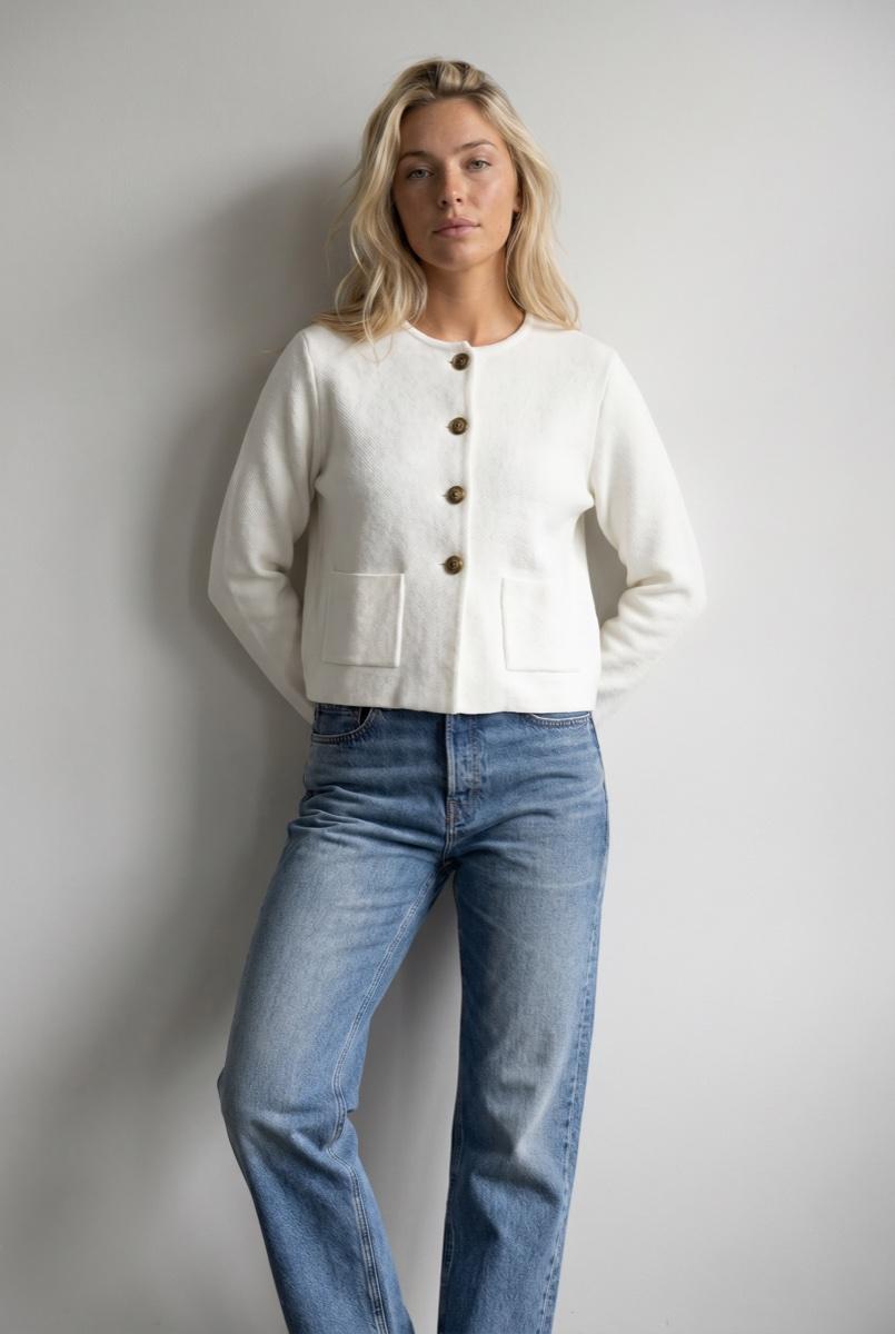 Model wearing a cropped white jacket with relaxed denim jeans, approved by QA