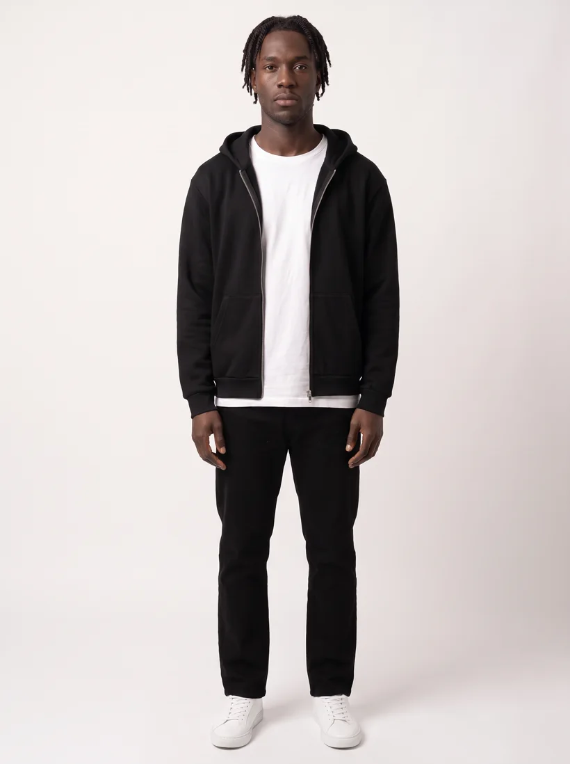 Full-body listing photo of a saved model wearing the black zip-up hoodie open over the white heavyweight tee on a light grey studio background, generated with Gemini Pro