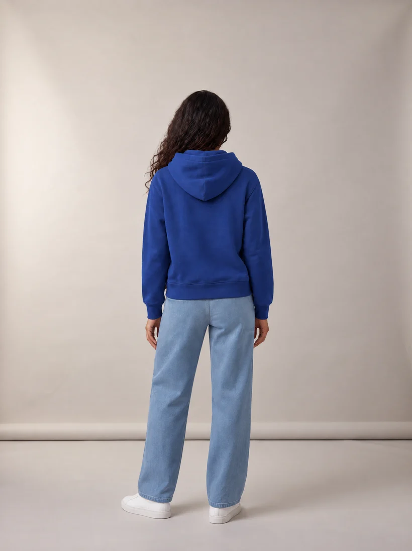 The same model from behind in the same pose and studio, now wearing the cobalt hoodie and light blue sweatpants, generated by a Uwear automation with GPT Image 2.5