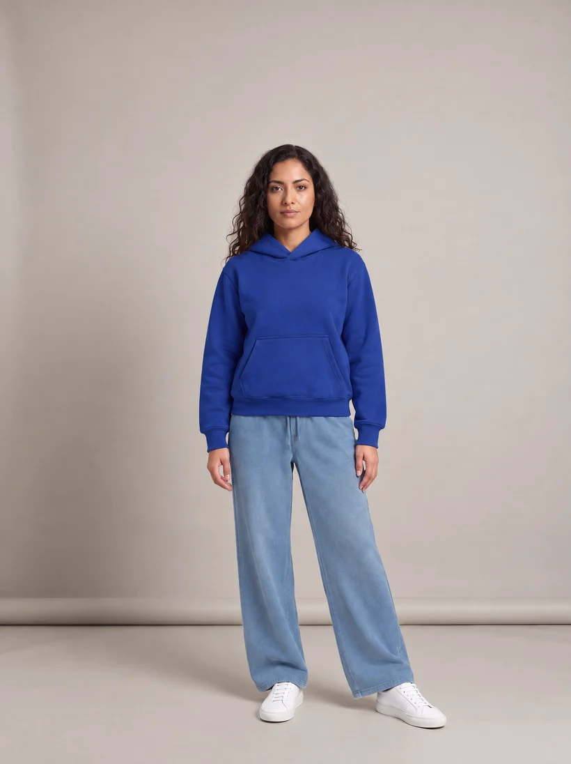 The same model in the same front pose and studio, now wearing a cobalt hoodie and light blue wide sweatpants, generated by a Uwear automation with GPT Image 2.5