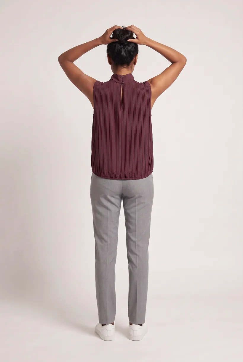 Model wearing the same pleated sleeveless high-neck blouse, full-body back camera edit on the Pure White studio, generated with nano-banana-pro through the Product page set template
